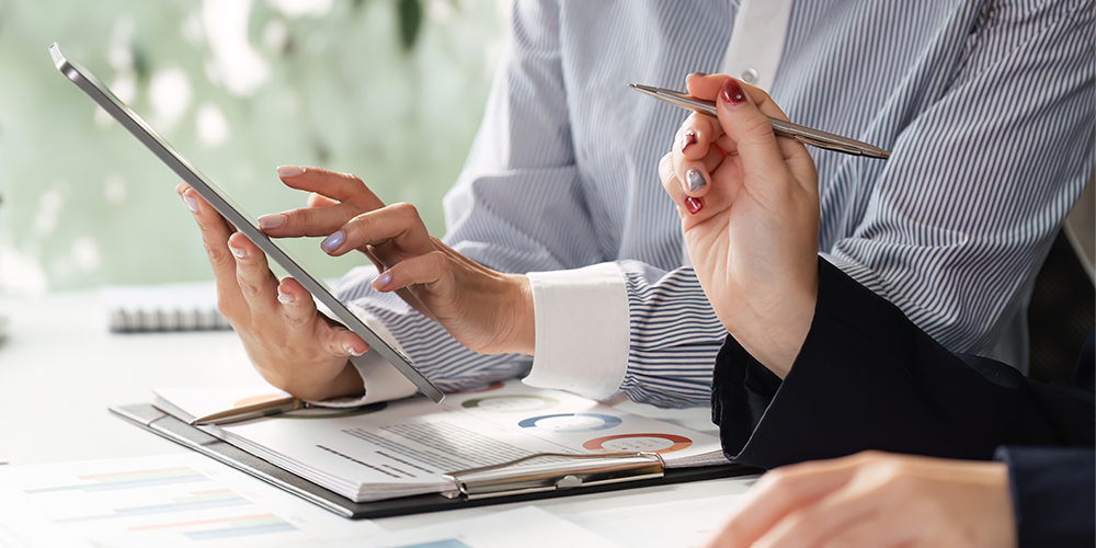Co-workers reviewing a document representing how Corporate Traveller delivers technology and expense solutions that allow you to manage your travel, get vital information about your travel patterns and stay in control of your travel expenses.