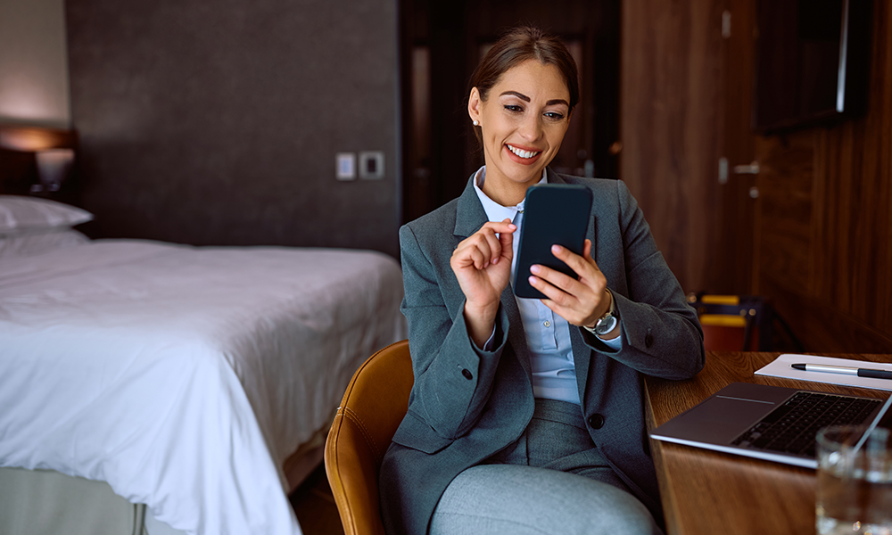 A woman sitting on a chair in her hotel room representing how travellers get an extra layer of traveller security with Safe & Secure. 