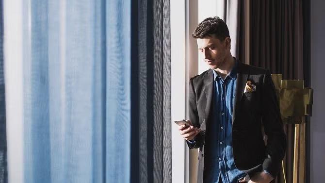 Man standing by a hotel window demonstrating how expert help can reduce the stress of business travel.