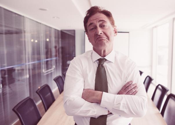 Man-standing-in-meeting-room-with-arms-crossed