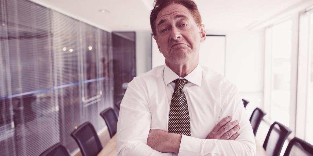 Man-standing-in-meeting-room-with-arms-crossed