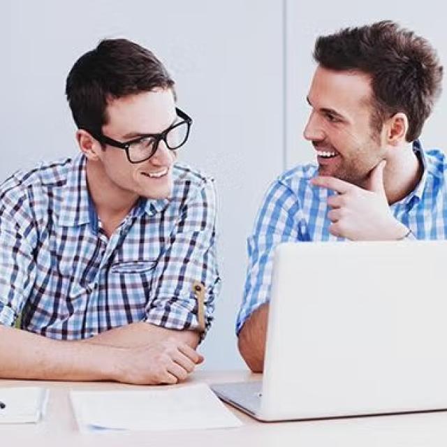 Two co-workers talking excitedly while looking at a laptop demonstrating how making some simple tweaks to its booking processes pulled Diadem out of its last minute booking compulsion.
