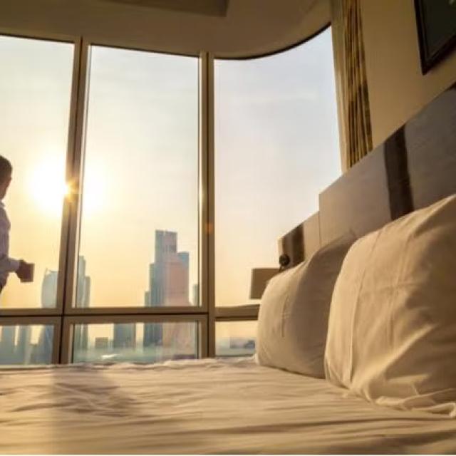 Man looking at city view from hotel room representing the best option for your hotel rates.