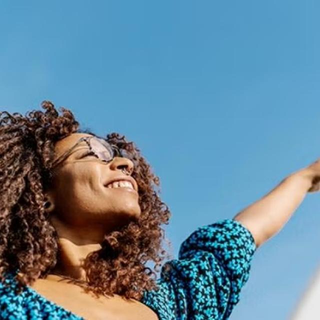 A woman waving here hands in happiness representing Money and stress saving reasons to outsource your business travel.