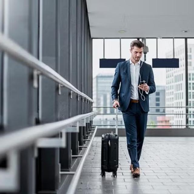 A man walking through the airport with a suitcase demonstrating the benefits of unpacking the basics of business travel.
